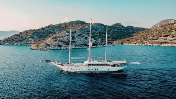 The gulet Bella Mare sails calmly in the waters off Bodrum, surrounded by a picturesque rocky coastline.