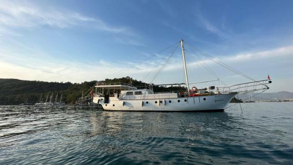 Die elegante Gulet Bohemian liegt vor Anker in ruhigem Wasser, umgeben von malerischer Küstenlandschaft.