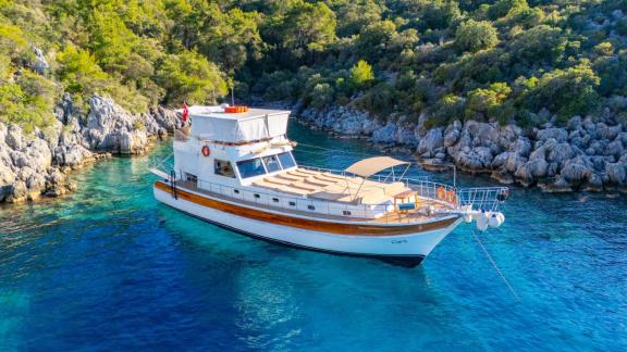 Die Gulet ÇağAy liegt in einer ruhigen, malerischen Bucht mit kristallklarem Wasser und grüner Küste bei Fethiye.