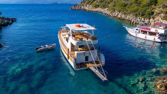 Die Gulet ÇağAy liegt vor Anker im kristallklaren Wasser von Fethiye, umgeben von atemberaubender Landschaft.