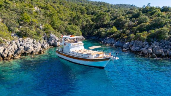 The Gulet ÇağAy is anchored in a secluded, crystal-clear bay surrounded by lush greenery near Fethiye.