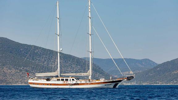 The elegant gulet Caner 4 sails off the coast of Bodrum, surrounded by picturesque hills and clear skies.