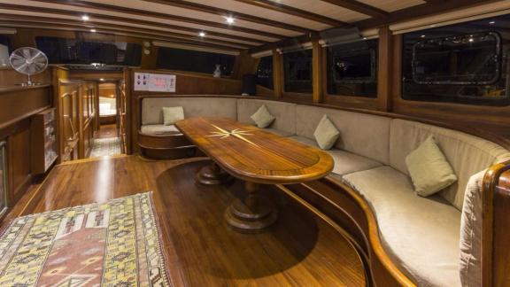 The saloon of Gulet Cemre 4 features a spacious seating area and a wooden dining table.