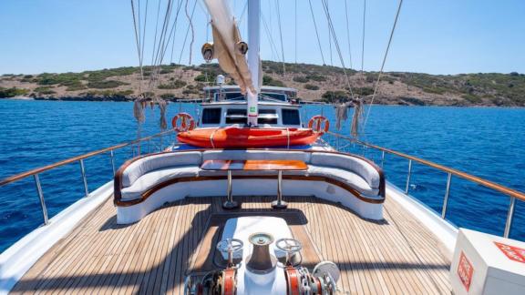 Foredeck seating area on Gulet Cemre Junior with a view of the turquoise sea.