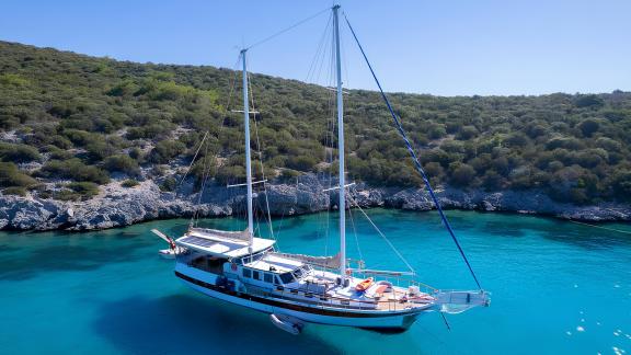 Gulet Cemre Junior is anchored in a quiet bay with clear blue waters.