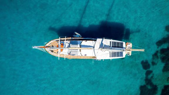 Aerial view of Gulet Cemre Junior peacefully resting on turquoise waters.