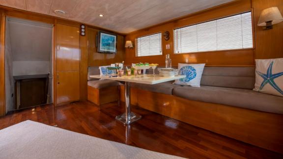 Dining area with table and sofas on Gulet Cemre Mila, decorated with nautical pillows.