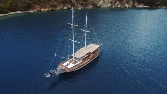 The Gulet Ceylan anchored in a quiet, secluded bay with clear water and green hills