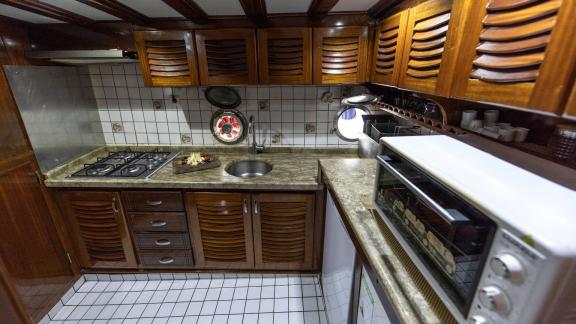 Fully equipped kitchen on Gulet Ceylan with stove, sink, oven, and wooden cabinets.