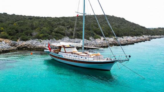 Enjoy the view of the Gulet Cosh anchored near a picturesque rocky shore in Bodrum.