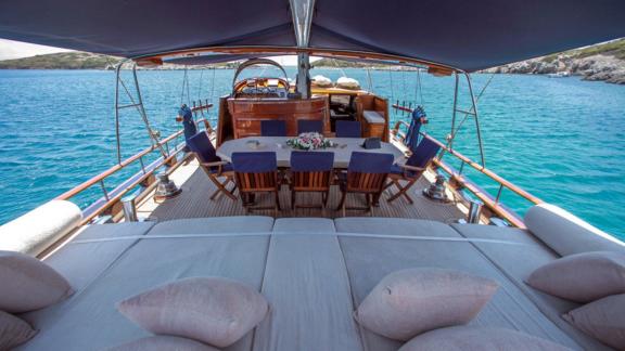 A comfortable sunbathing area and a dining area on the deck of the gulet Dulcinea, anchored in an idyllic bay.