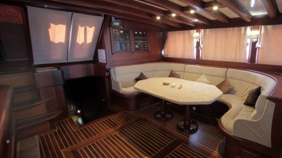 A stylish saloon on board the Gulet Dulcinea with a cosy seating area and an elegant dining table.