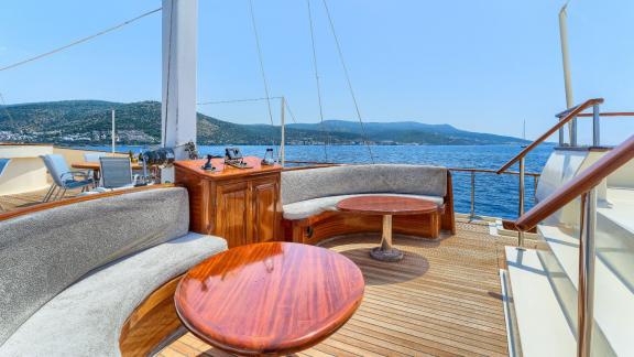 Cosy seating area with round tables, wooden furniture and panoramic views of the sea and coastline