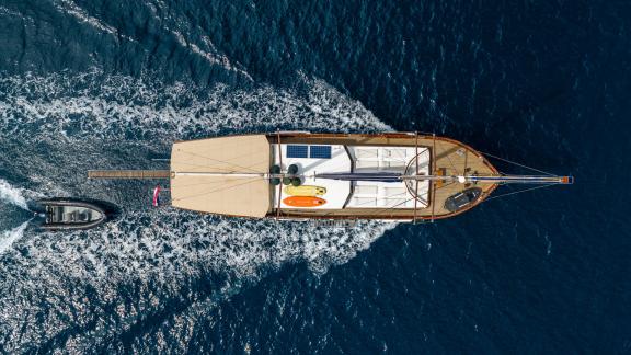 Luftaufnahme der Gulet Eleganza, die mit einem Beiboot durch das blaue Meer vor Split fährt.