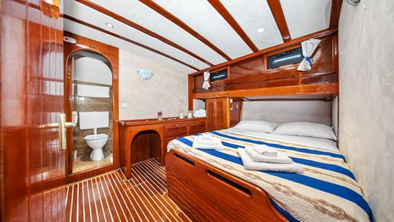Die Kabine mit Holzinterieur verfügt über ein Doppelbett, ein Bad und kleine Fenster.