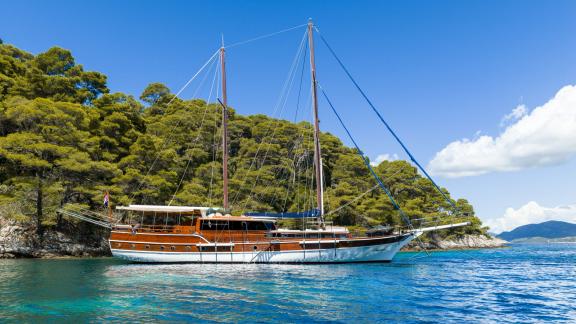 Die Gulet Eleganza liegt in türkisfarbenem Wasser mit Blick auf den Wald, ideal für einen ruhigen Urlaub.
