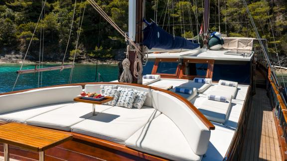 Auf dem Bugdeck der Gulet Eleganza in einer türkisfarbenen Bucht befinden sich bequeme Liegen und Erfrischungen.