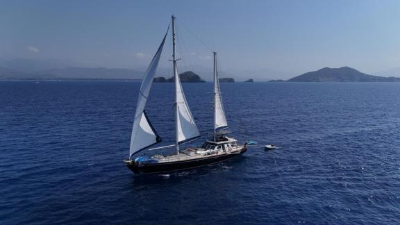 Among Marmaris yacht rental options Eloa is sailing in open sea with sails up and island views in background.