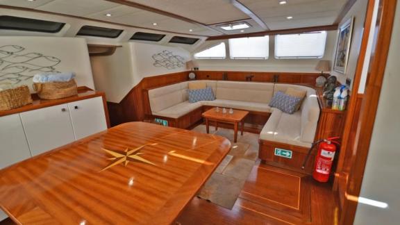 Among Marmaris yacht rental options Eloa interior shows corner seating area with large dining table for comfort.