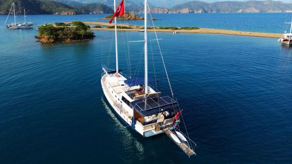 Die Gulet Emir Bey 1 liegt in einer malerischen Bucht von Göcek vor Anker, umgeben von ruhigem Wasser und idyllischer Na