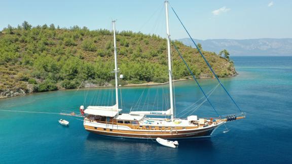 The yacht Enderim A anchors in Bodrum's clear waters in front of green hills.