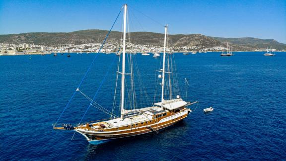 Die Yacht Enderim A segelt in Bodrum mit Blick auf die Stadt und umliegende Hügel.