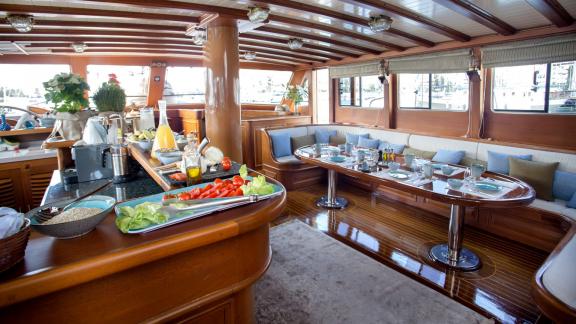 Rich breakfast buffet on the gulet Entre Cielos with a cosy seating area and elegant wooden furnishings.