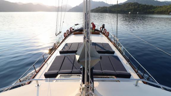 Blick auf das Deck der Gulet Erden mit Sonnenliegen, umgeben von ruhigem Wasser und Hügeln.