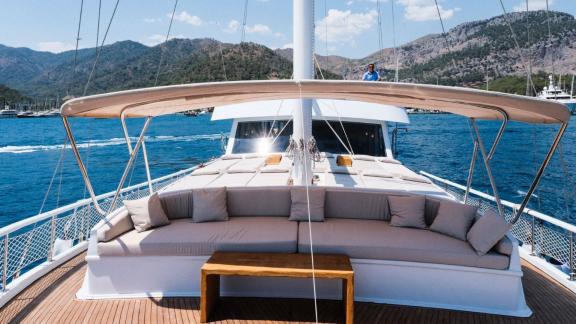 Spacious seating area on the deck of a gulet with surrounding mountain scenery.