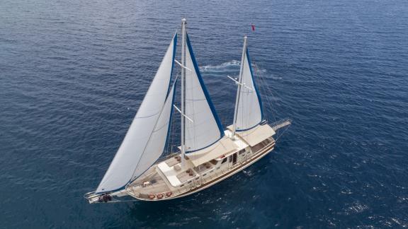 Beautiful 4-cabin gulet with sails set on the open, calm sea.