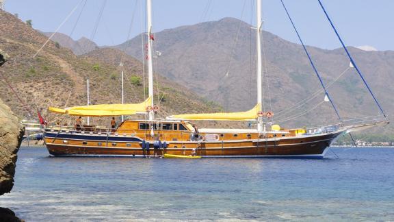 Bodrum-Gulet mit 8 Kabinen namens Flas VII, die friedlich in einer malerischen Bucht vor Anker liegt, umgeben von bergig