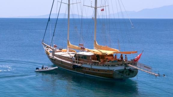 Die Flas VII liegt friedlich vor Anker, während ein Beiboot anlegt.