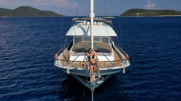 A woman poses on the bow of the gulet Freedom, anchored in the blue waters of Marmaris.