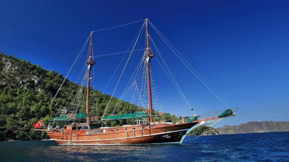 Elegante Gulet segelt vor der üppig bewaldeten Küste von Marmaris unter klarem Himmel