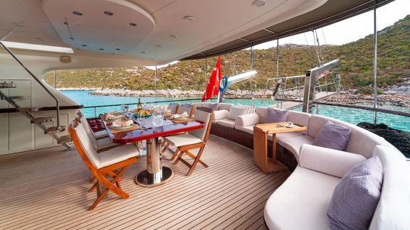 In Göcek gulet charter option Getaway aft deck with dining table seating area and sea view visible.