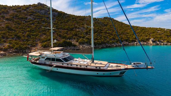 In Göcek gulet charter option Getaway anchored in clear water with spacious deck and sunbathing area visible.