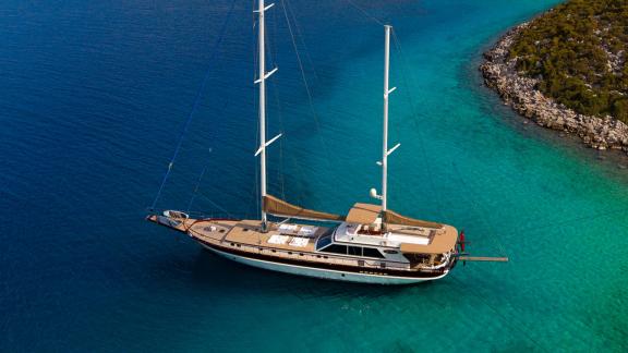 In Göcek gulet charter option Getaway aerial view in turquoise bay with spacious deck and sunbathing area visible.