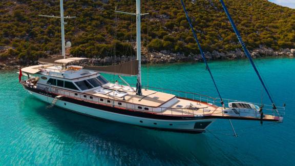 In Göcek gulet charter option Getaway side view in clear water with spacious deck and sunbathing area visible.