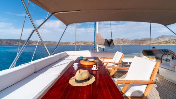 In Göcek gulet charter option Getaway flybridge with seating area table and panoramic sea view visible.