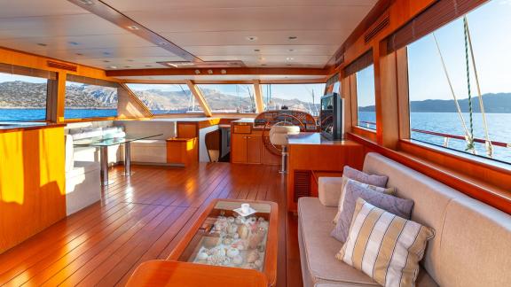 In Göcek gulet charter option Getaway salon with helm station seating area and large windows with sea view visible.