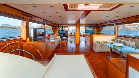 In Göcek gulet charter option Getaway interior salon with seating area tv and panoramic sea view visible.