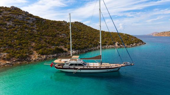 In Göcek gulet charter option Getaway anchored in calm bay with nature view and spacious deck visible.