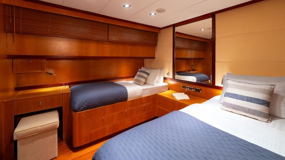In Göcek gulet charter option Getaway cabin with two single beds mirror and storage space visible.