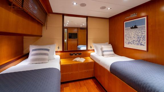 In Göcek gulet charter option Getaway cabin with two single beds mirror and lighting comfortable interior visible.