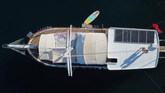 Draufsicht auf eine Segelyacht mit Solarpanel und Paddleboard im Wasser.