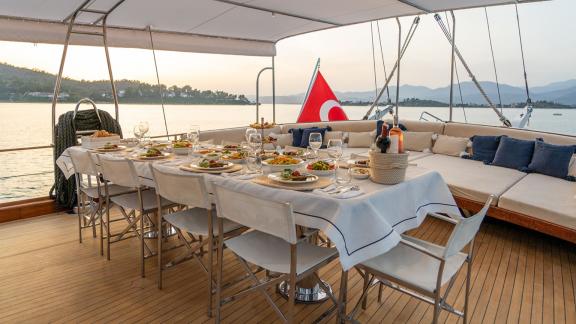 In Fethiye gulet charter option Happy Days aft deck with prepared dining table and seating area visible.