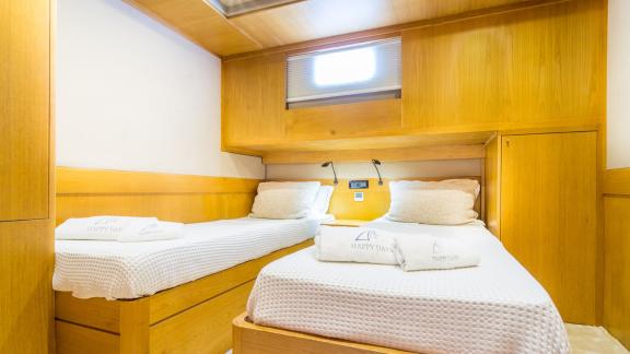 In Fethiye gulet charter option Happy Days cabin with two single beds and window visible.