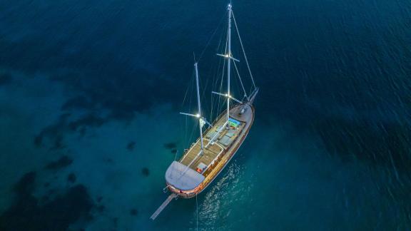 Beleuchtete Segelyacht bei Nacht auf ruhigem, klarem Wasser vor der Küste von Bodrum.