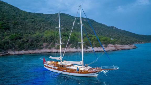 Gulet-Yacht Jasemin 1 im türkisfarbenen Wasser vor bewaldeter Küste.