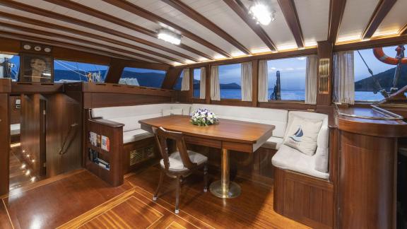 Elegant interior of the gulet yacht Jasemin 1, with cosy seating area and dining table, offers a view of the sea.